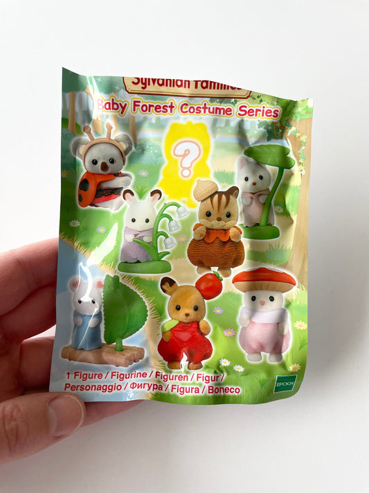 You pick Calico Critters baby forest costume series blind bag figures. Sylvanian Families collectible baby critters in fairytale outfits like mushroom, ladybug, a leaf boat, and apple. Comes brand new out of box, no guess work!