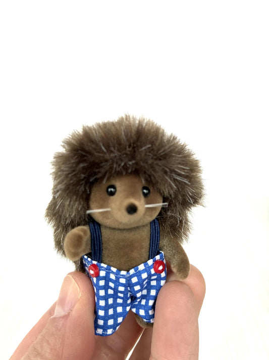 Calico Critters Sylvanian Families Pickleweeds Bramble hedgehog brother in blue gingham dungarees, front view held in hand