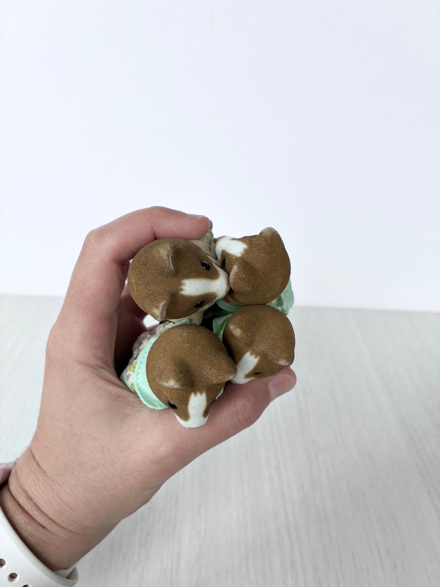 Calico Critters Sylvanian Families hound dog figures held in hand for scale
