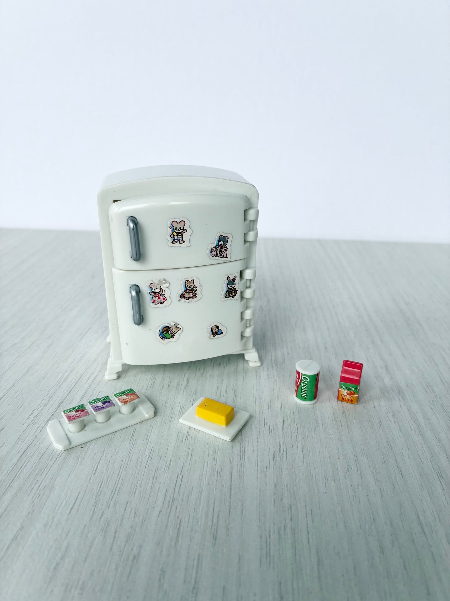 Calico Critters Sylvanian Families white refrigerator with food accessories laid out in front