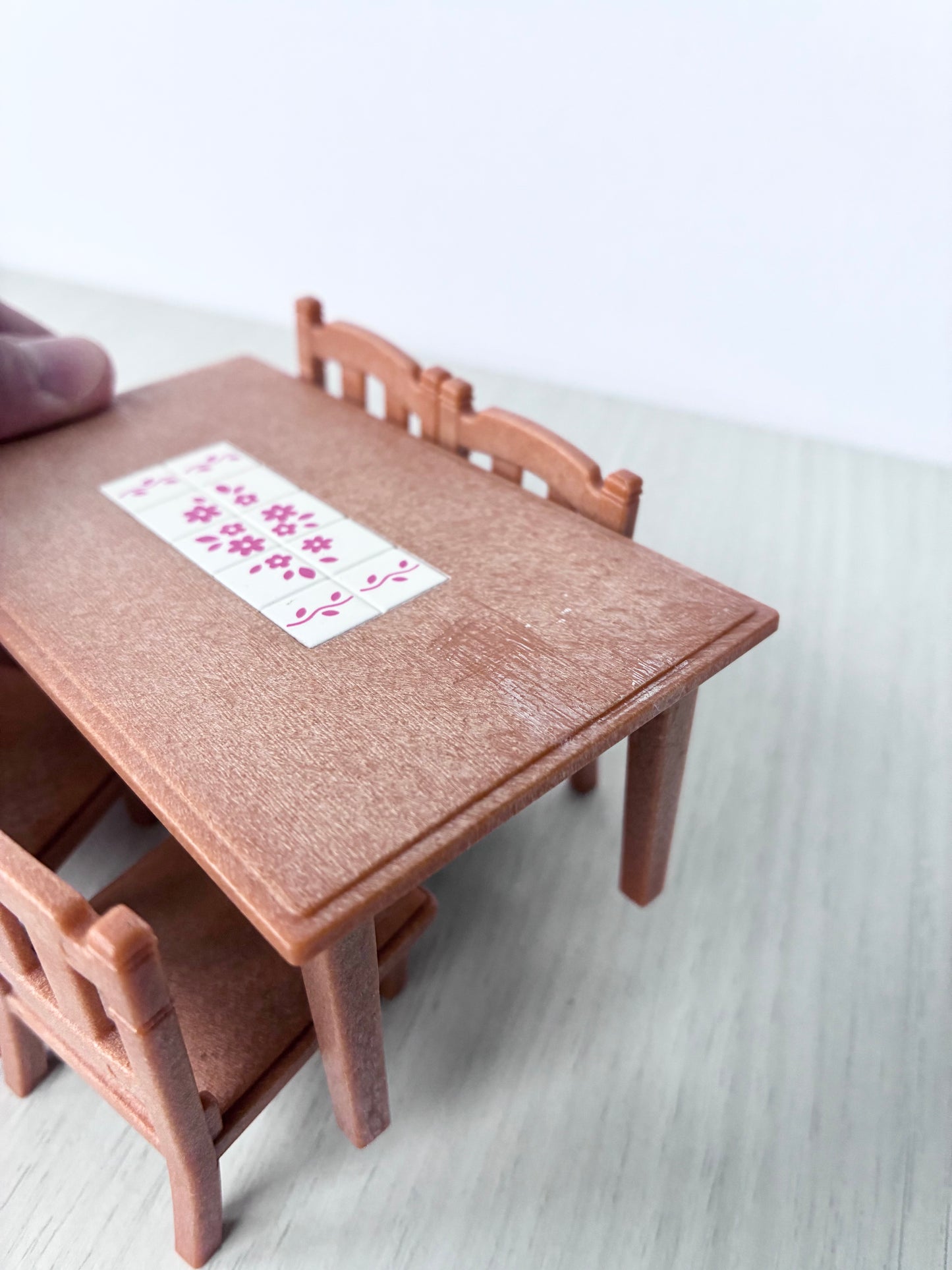 Top view of Calico Critters Sylvanian Families dining table showing pink floral tile inlay and light surface wear