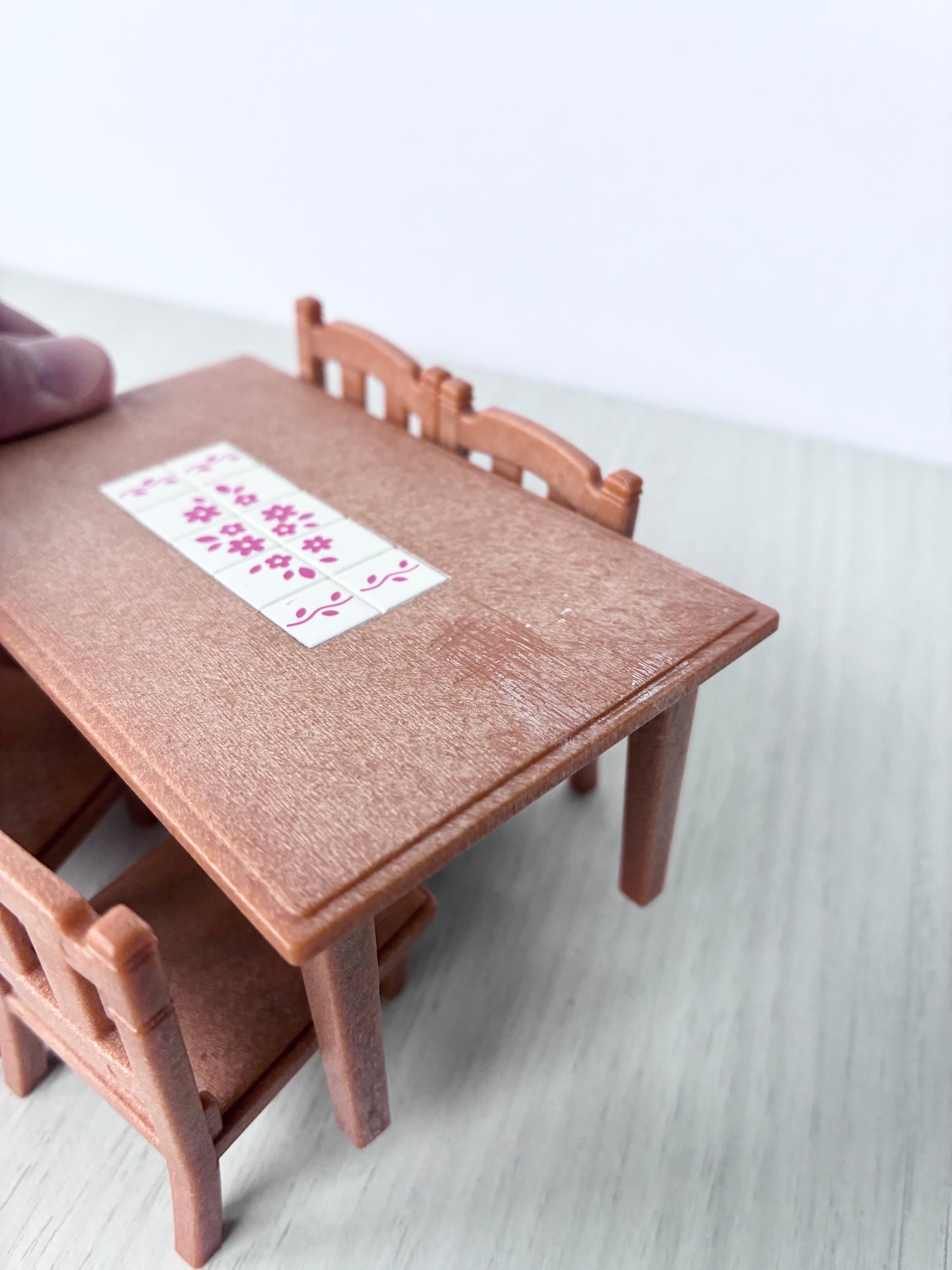 Top view of Calico Critters Sylvanian Families dining table showing pink floral tile inlay and light surface wear