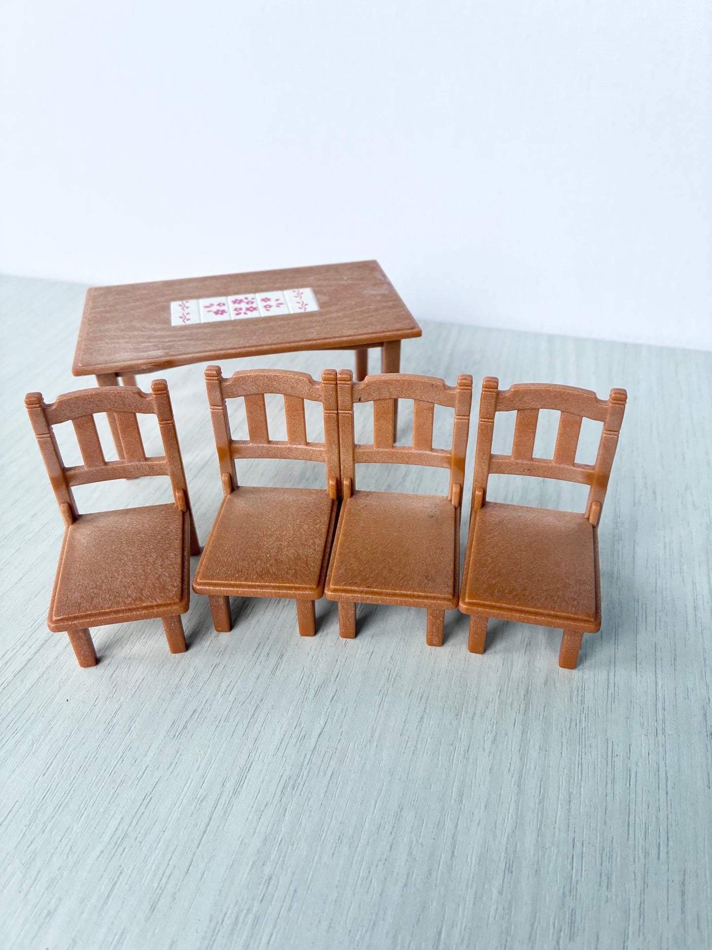 Four matching Calico Critters Sylvanian Families dining chairs lined up beside the table