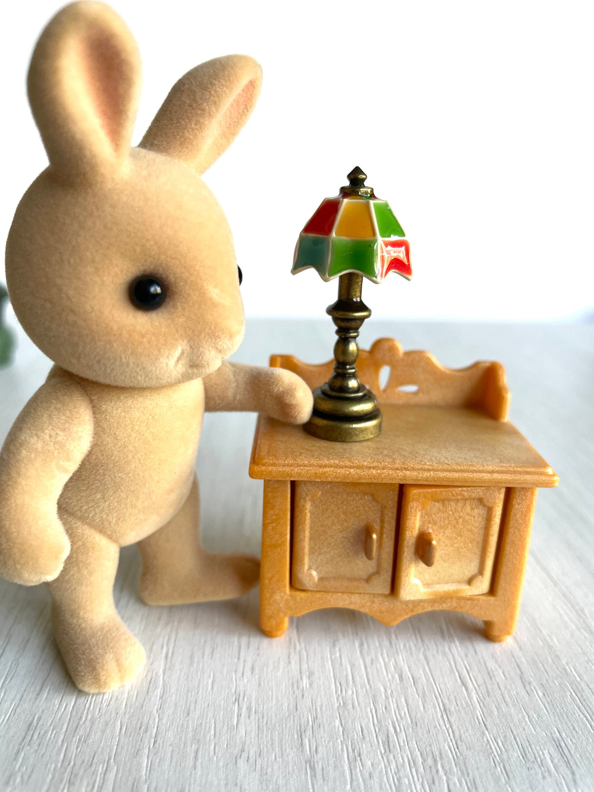 Miniature tiffany lamp with bronze base and colorful lampshade. Tiny Calico Critters bunny next to the light for scale showing the perfect Sylvanian size.