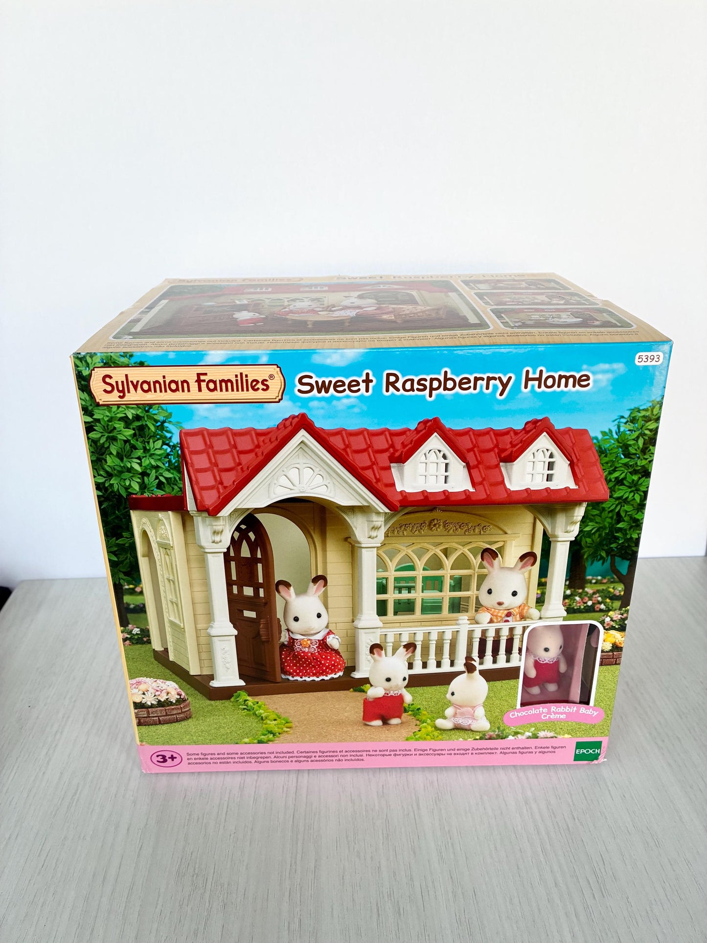 May include: A boxed Sylvanian Families Sweet Raspberry Home playset. The box features a miniature house with a red roof, white trim, and several bunny figures. The box also includes the text "Sweet Raspberry Home" and the Sylvanian Families logo.