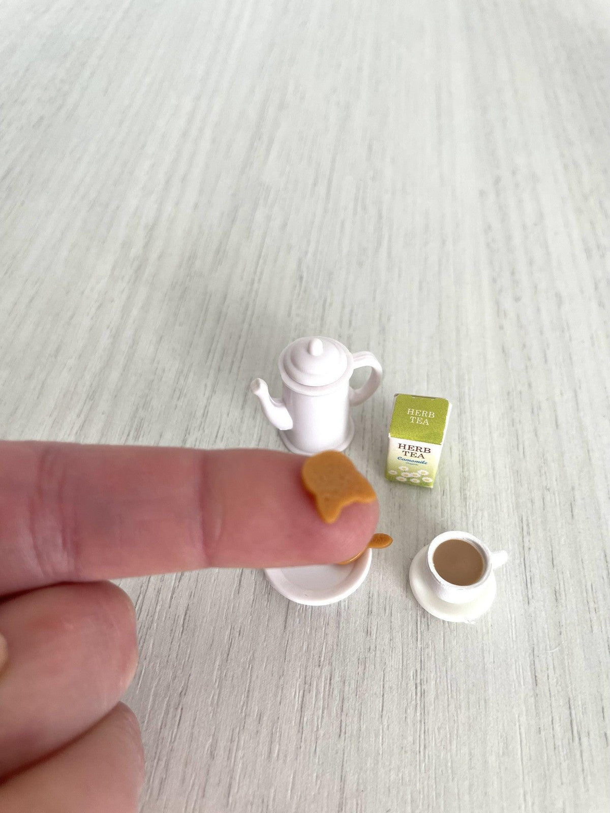Rabbit-shaped biscuit shown on a fingertip for scale — Calico Critters and Sylvanian Families