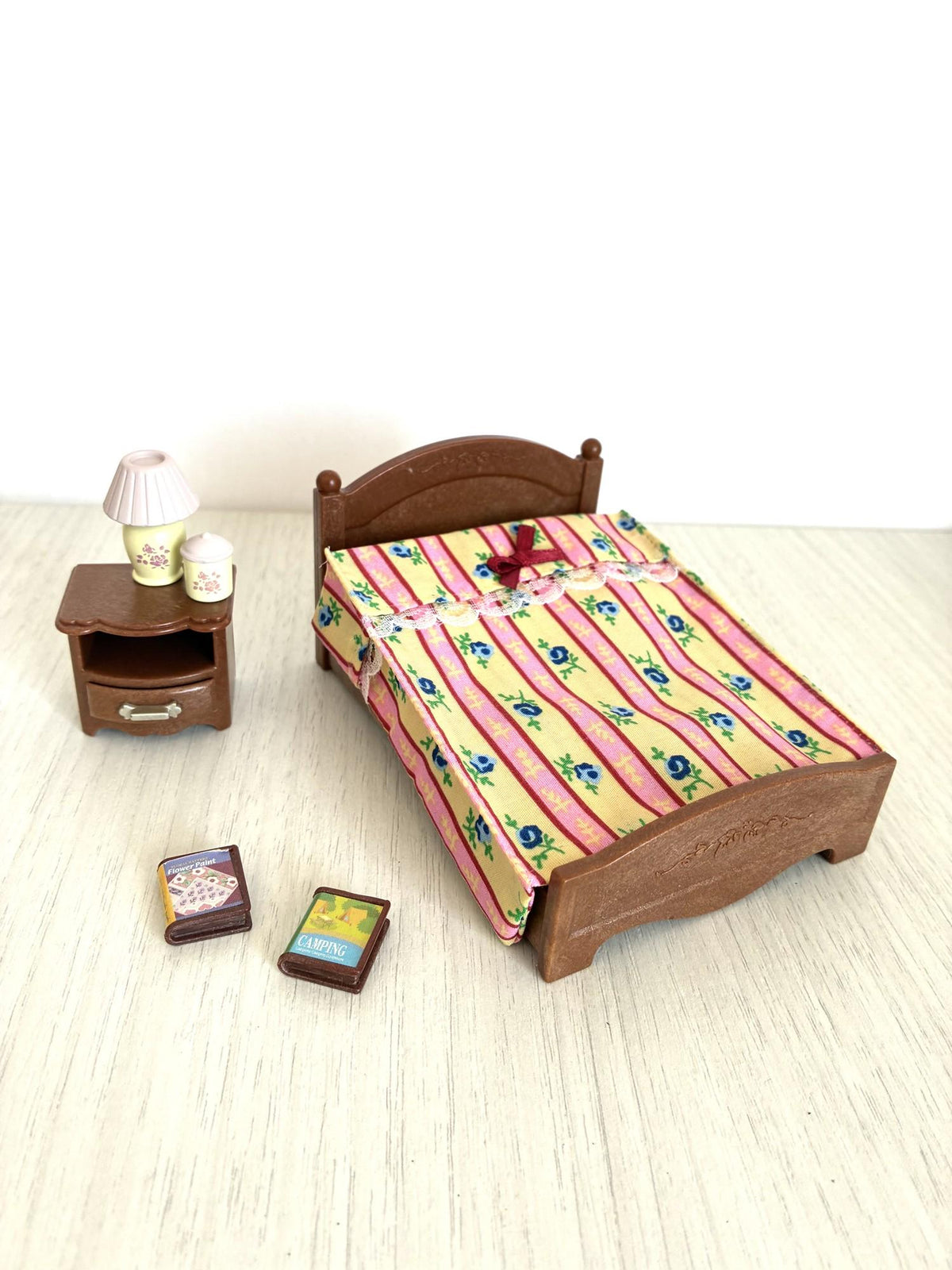 Calico Critters Sylvanian Families double bed with floral striped quilt, bedside table, lamp and books, dollhouse bedroom set