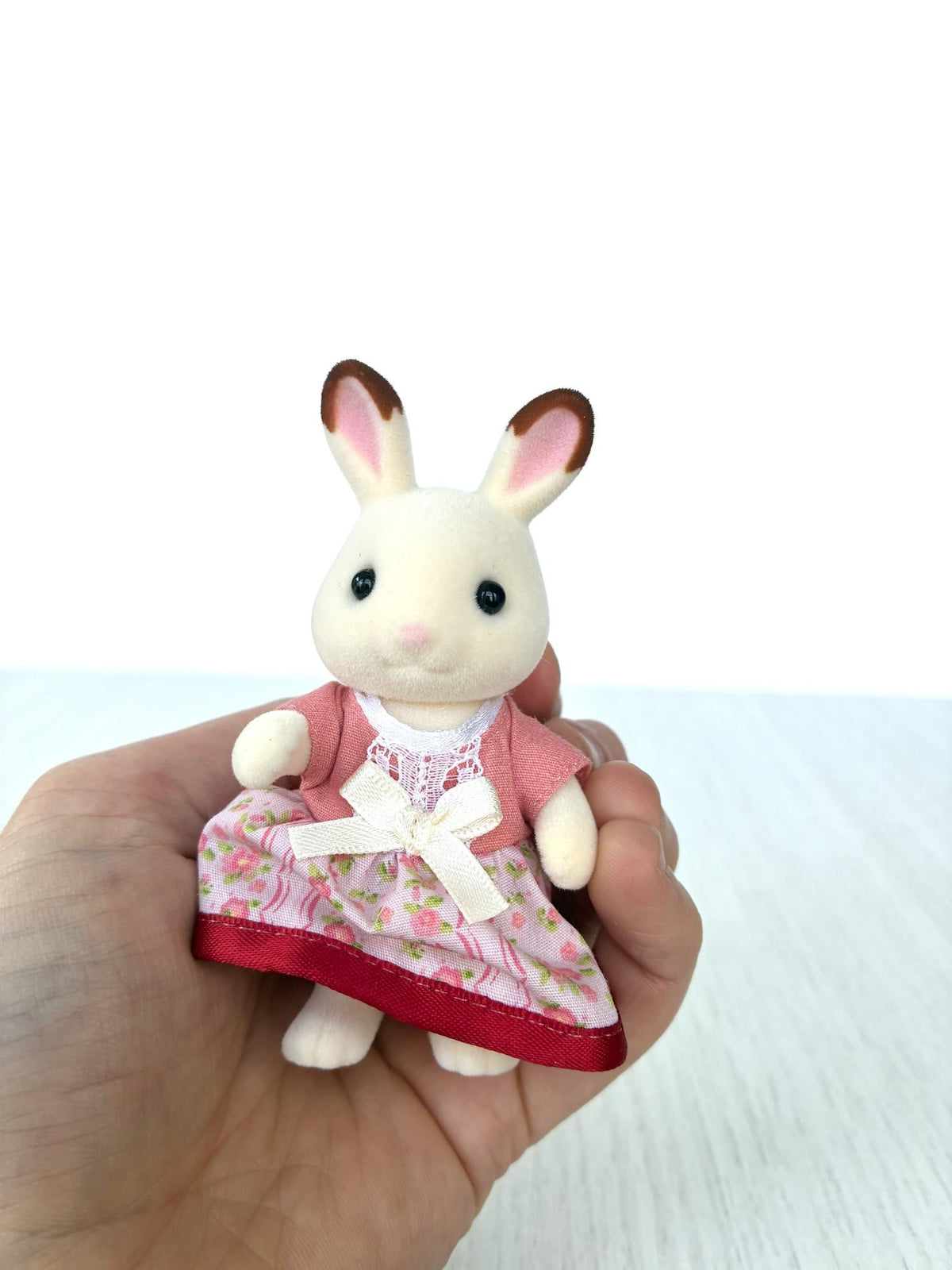 Calico Critters Sylvanian Families Hopscotch Chocolate rabbit mother in pink floral dress with bow, front view held in hand
