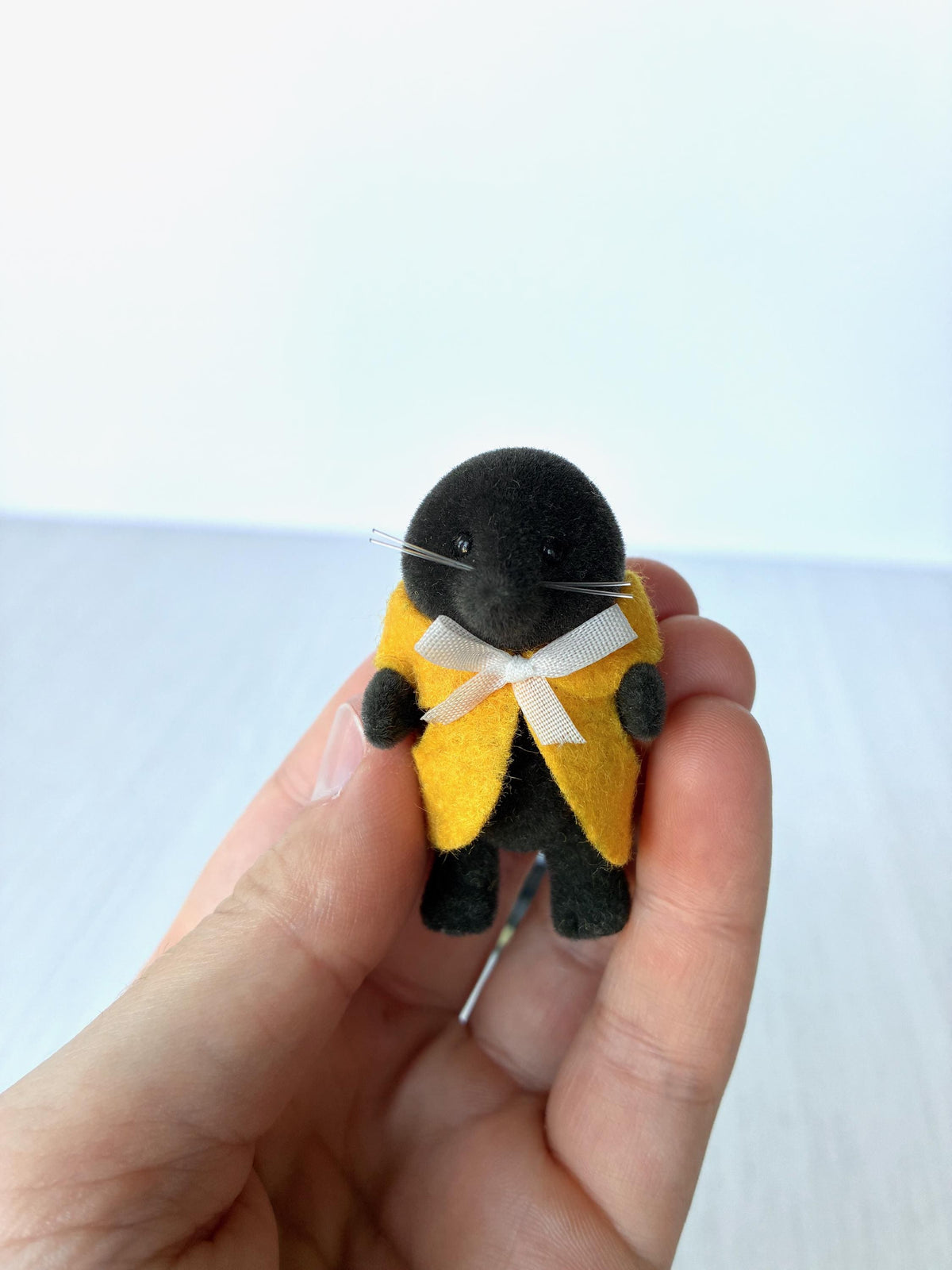 Calico Critters Sylvanian Families vintage McBurrows mole family, child mole in a yellow felt cape with white ribbon, held in hand for scale