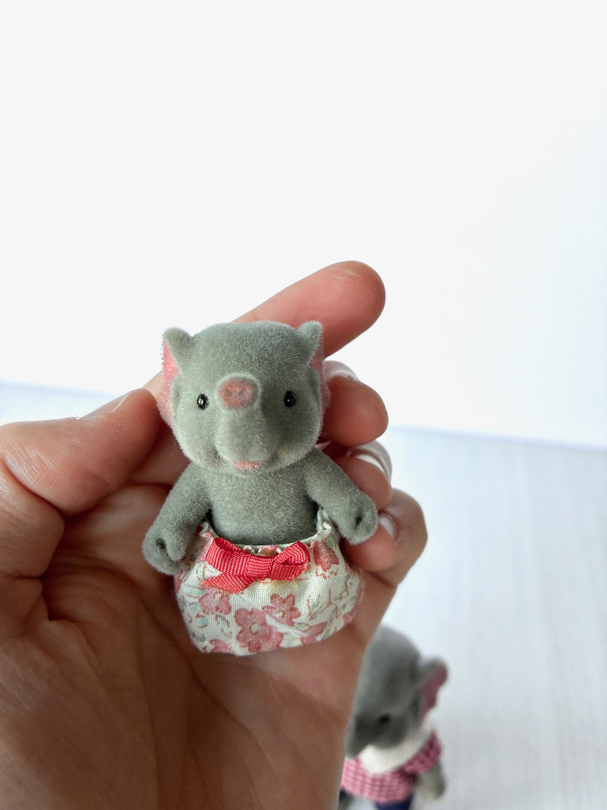 Bärenwald Forest Families elephant sister in pink floral skirt, held in hand for scale