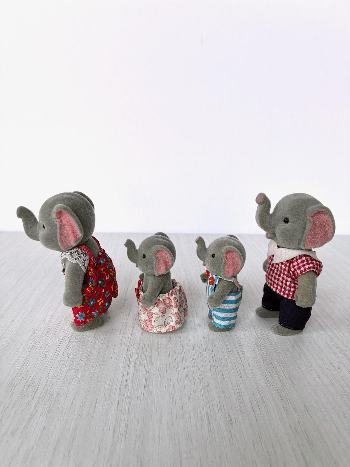 Vintage Bärenwald elephant family of four, side view showing light grey flocking and outfits