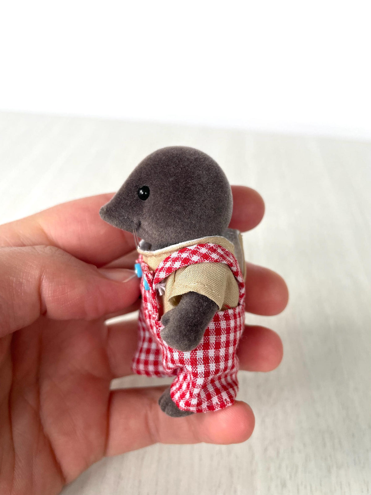 Mole dad held in hand, side profile showing the blue buttons on the red gingham overalls — Calico Critters and Sylvanian Families