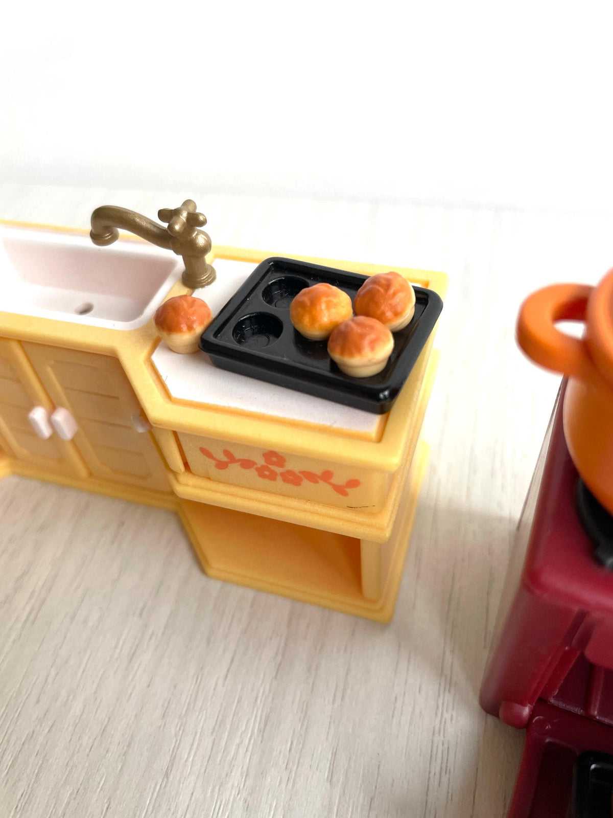Close up of the cream kitchen sink unit with brass tap and black hob, vintage Calico Critters Sylvanian Families kitchen