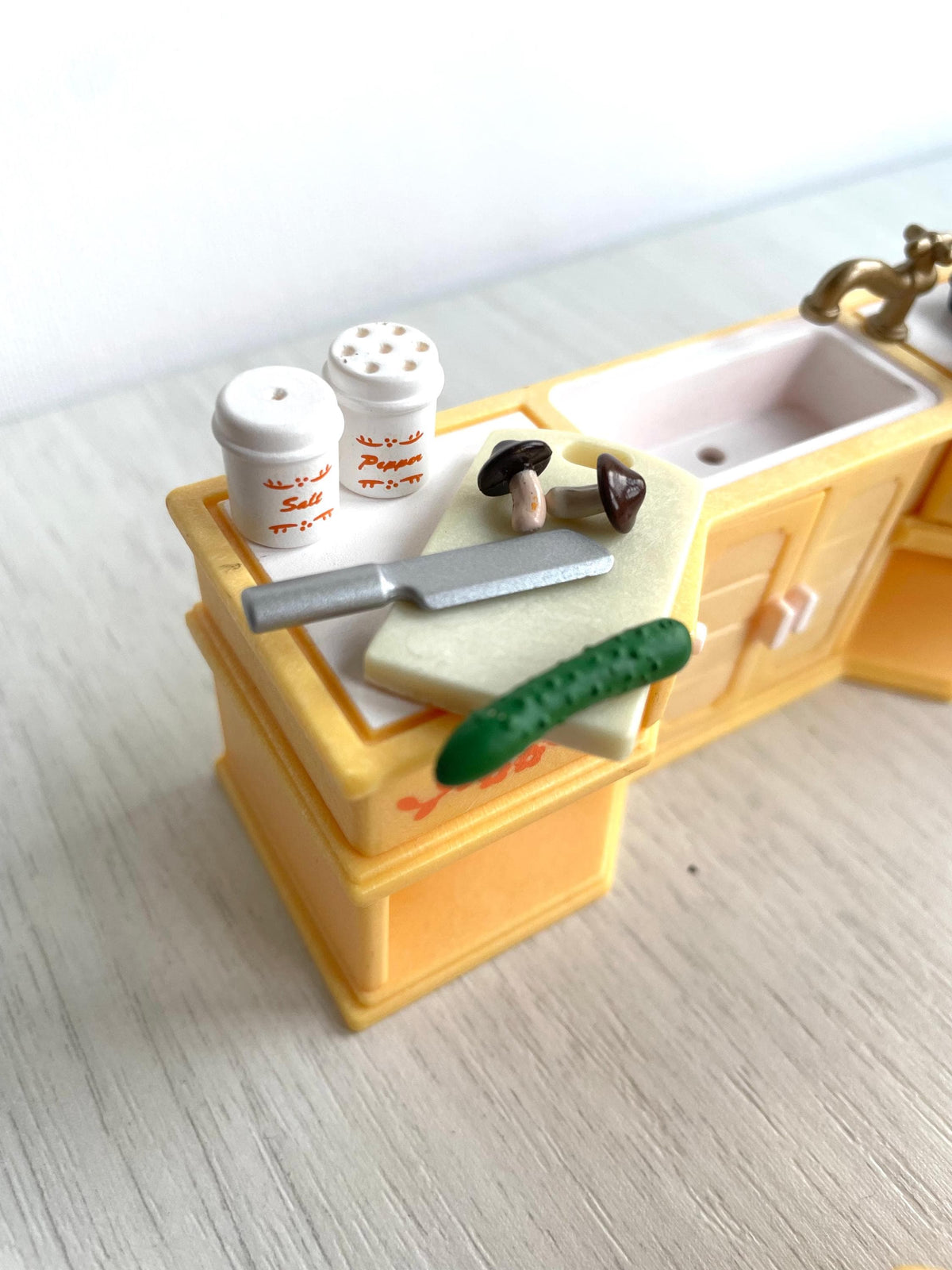 Detail of the counter top with salt and pepper shakers, chopping board, knife, cucumber and mushrooms, Calico Critters Sylvanian Families kitchen