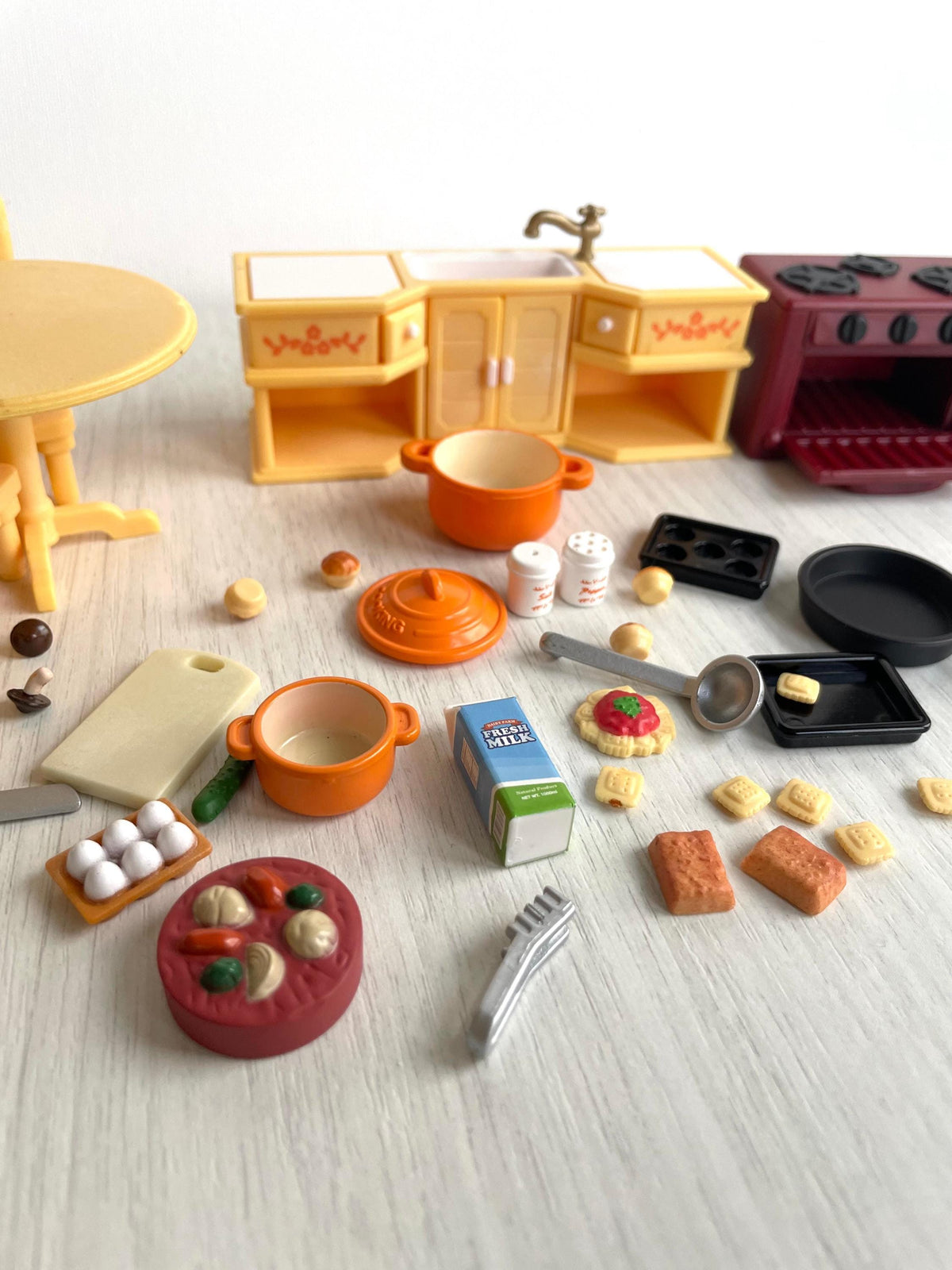 Everything included in the vintage Calico Critters Sylvanian Families kitchen set laid out together, furniture, cookware and food pieces
