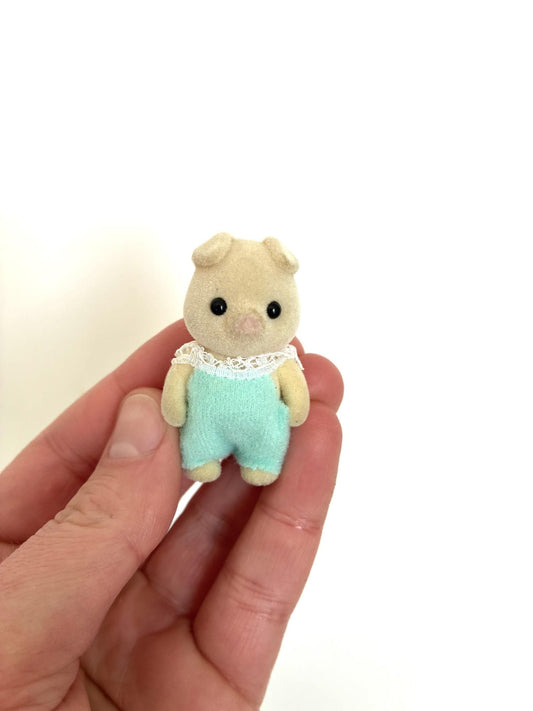 Calico Critters Sylvanian Families cream pig baby in mint green romper, standing jointed baby, front view held in hand