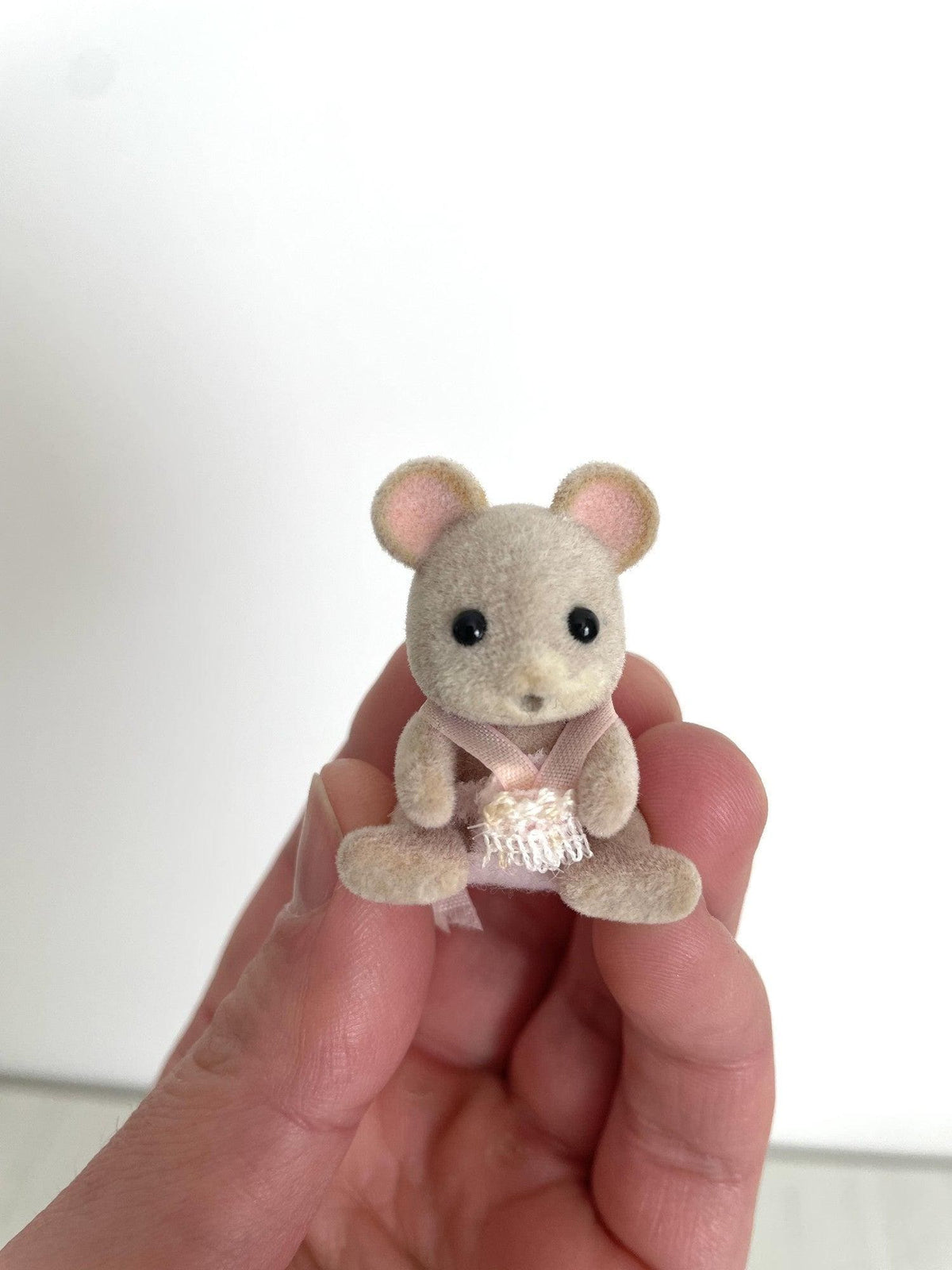 Maces Mouse baby girl in pink romper held in hand, front view — Calico Critters and Sylvanian Families