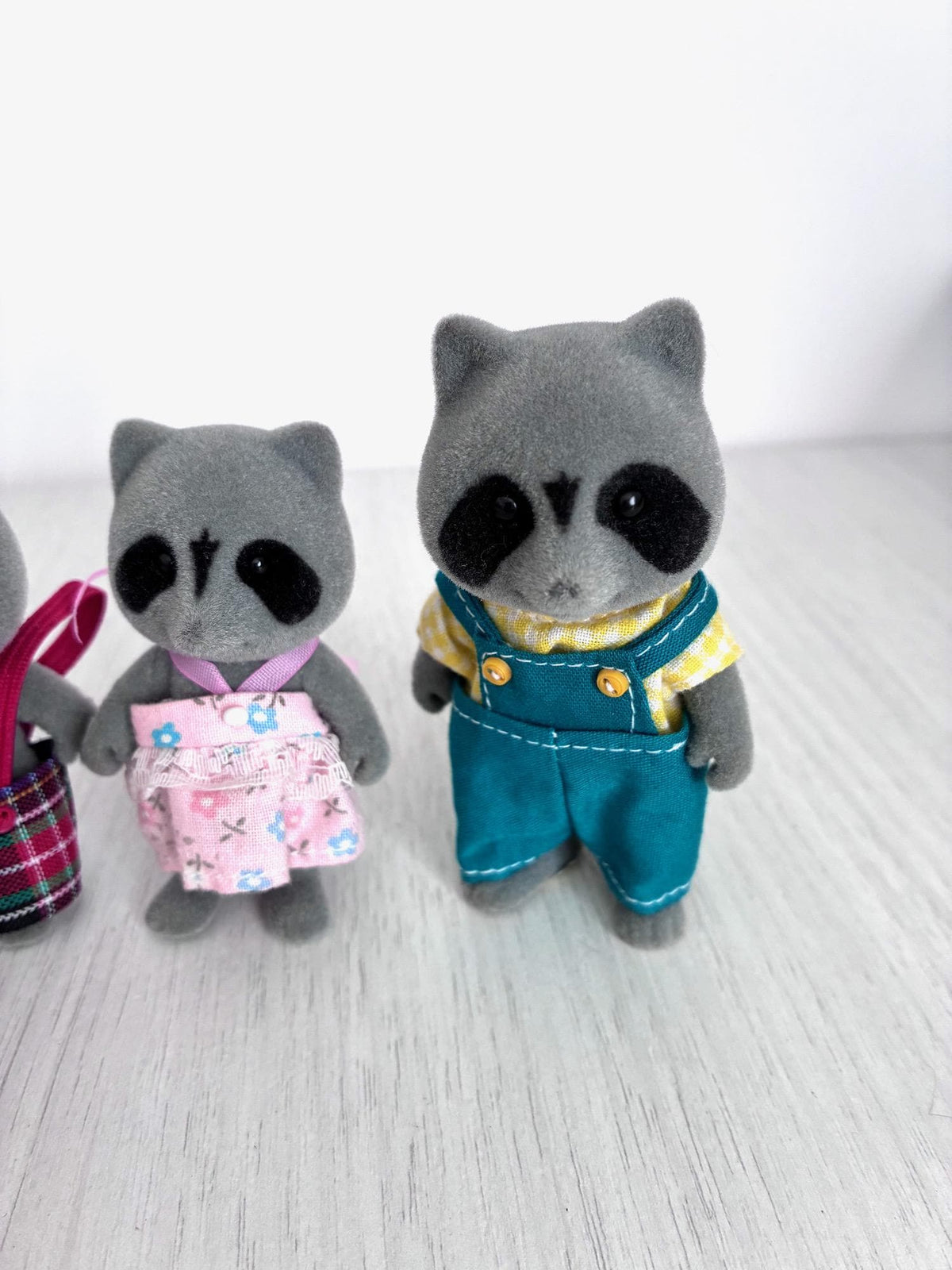 Calico Critters Sylvanian Families vintage Chestnut Raccoon family of 4, sister in pink floral skirt beside father in teal overalls and yellow shirt
