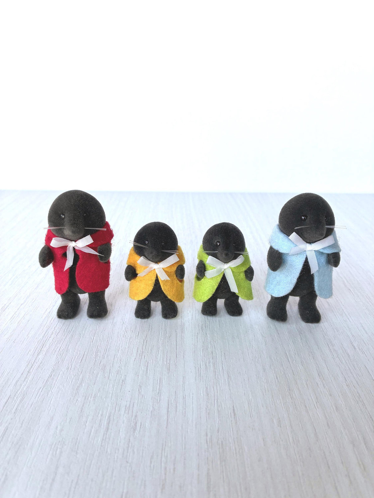 Calico Critters Sylvanian Families vintage McBurrows mole family of four standing together, dad in red cape, two children in yellow and green, mum in blue