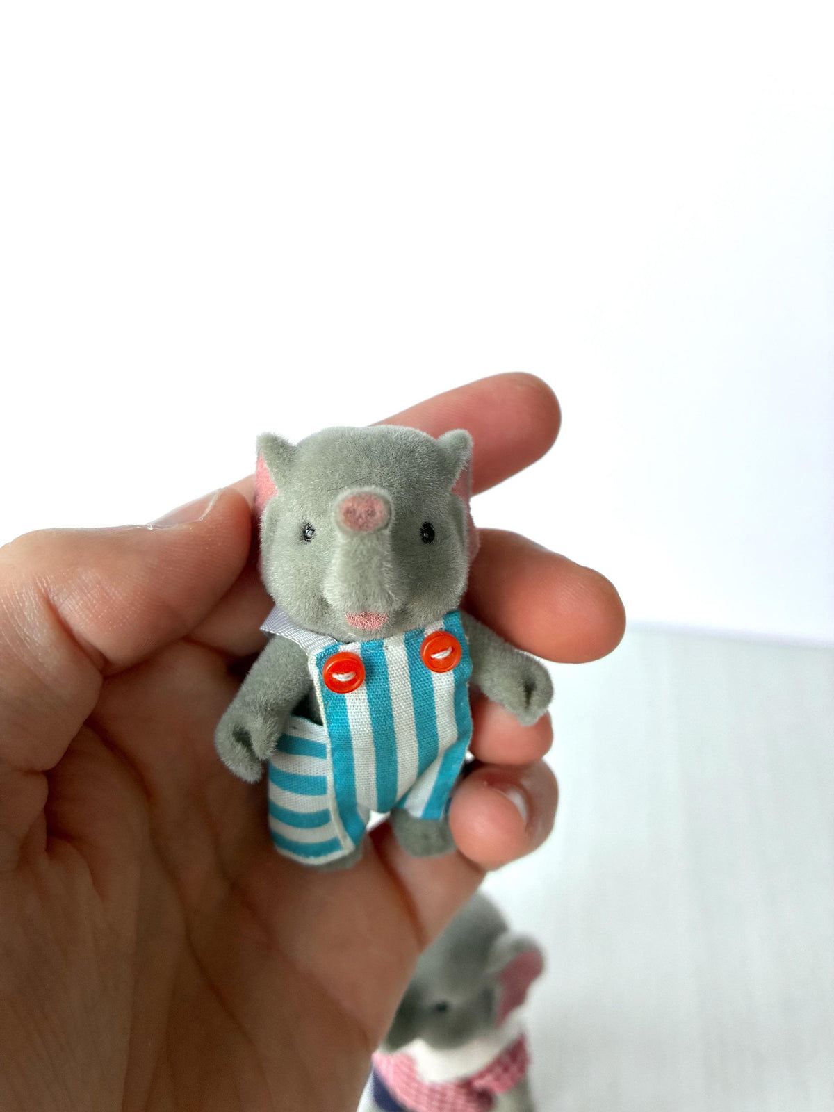 Bärenwald Forest Families elephant brother in blue striped dungarees with orange buttons, held in hand for scale