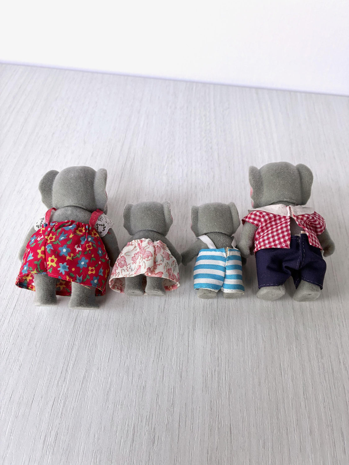 Rear view of the four vintage Bärenwald elephants showing the backs of the dress, skirt, dungarees and trousers