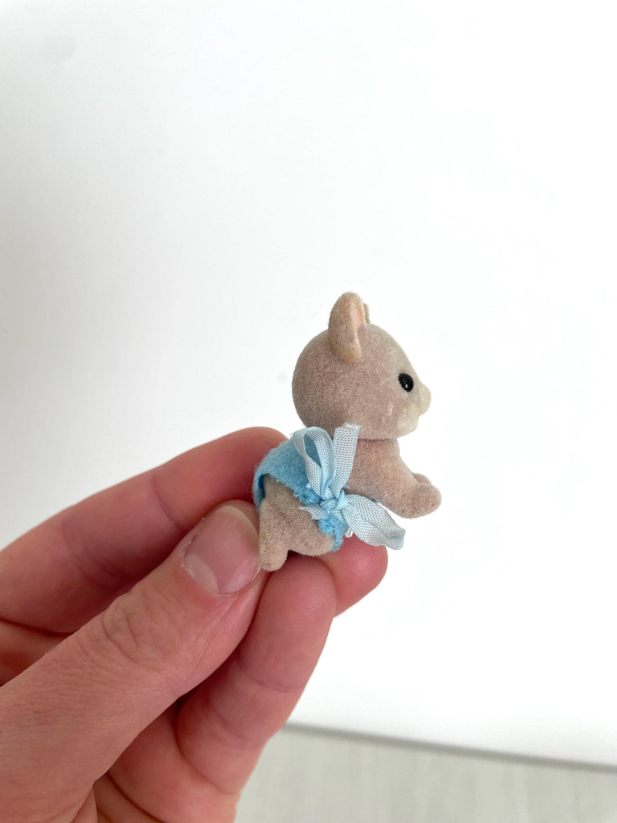 Maces Mouse baby boy held in hand, three-quarter profile showing his pink ears — Calico Critters and Sylvanian Families