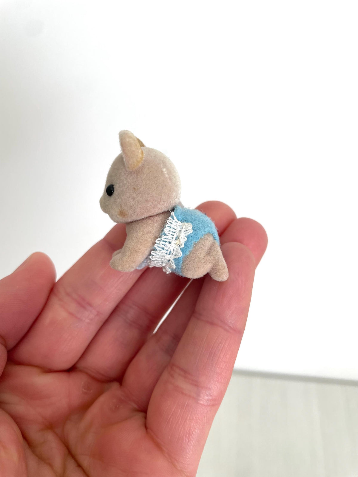 Maces Mouse baby boy held in hand, back three-quarter view of the blue romper and lace trim — Calico Critters and Sylvanian Families