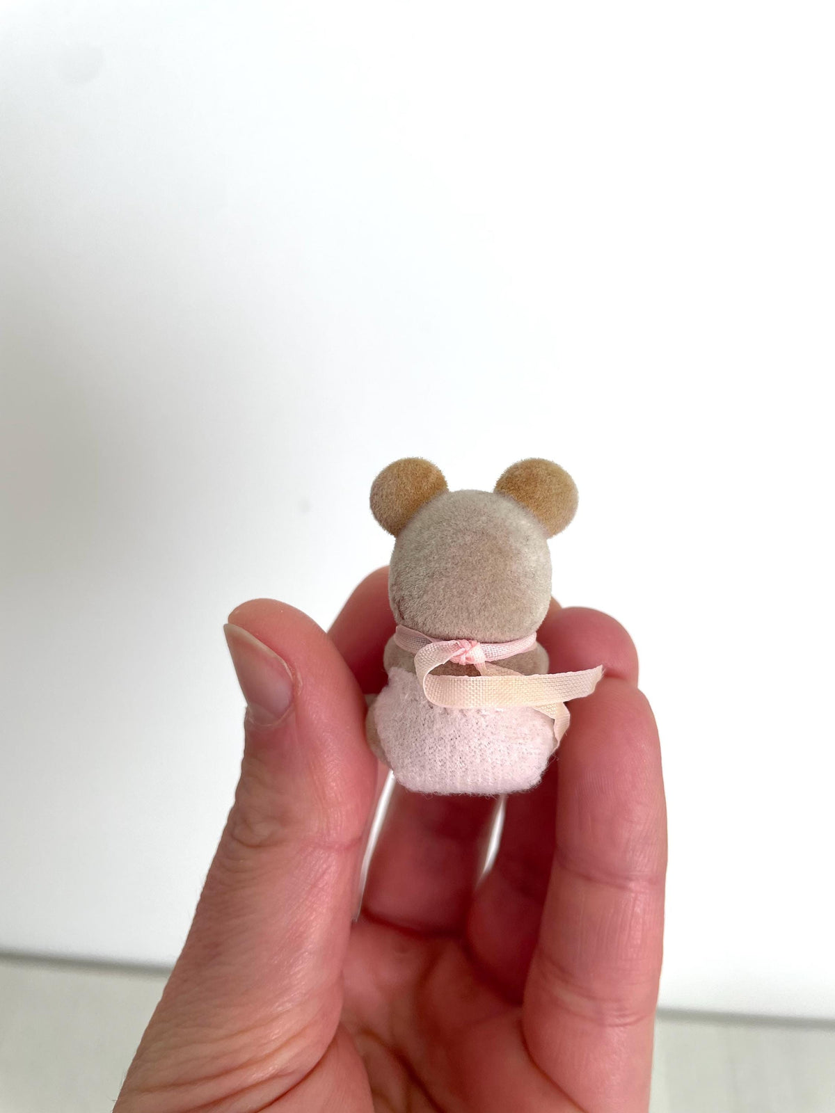 Maces Mouse baby girl held in hand, back view showing her round ears and pink bow — Calico Critters and Sylvanian Families