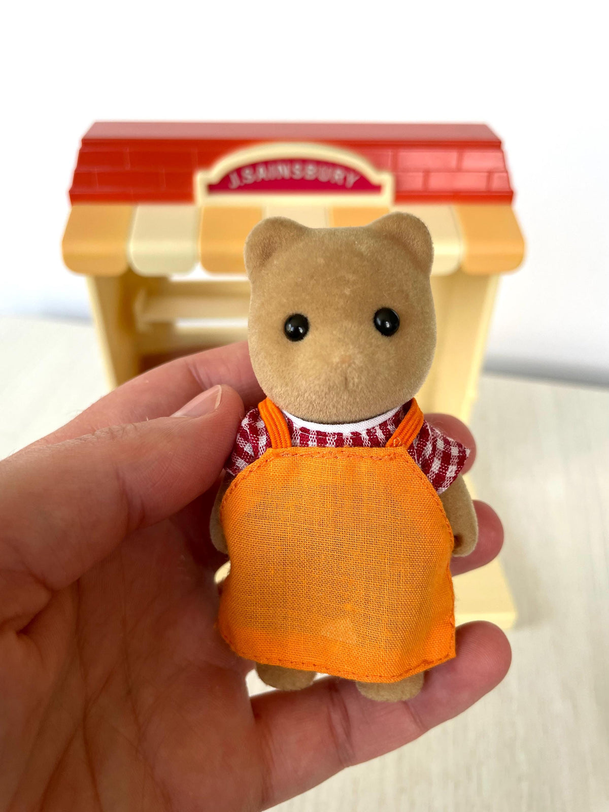 Sylvanian Families J. Sainsbury shopkeeper bear in orange apron and red check shirt, Calico Critters
