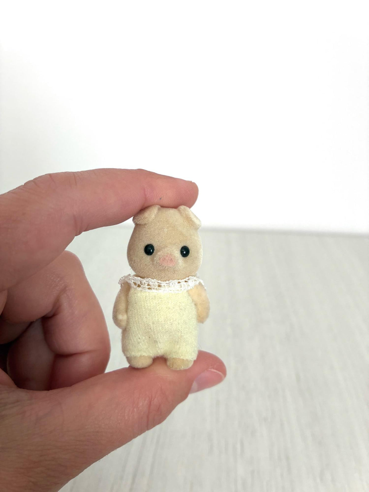 Calico Critters Sylvanian Families piglet baby, front view held between fingers