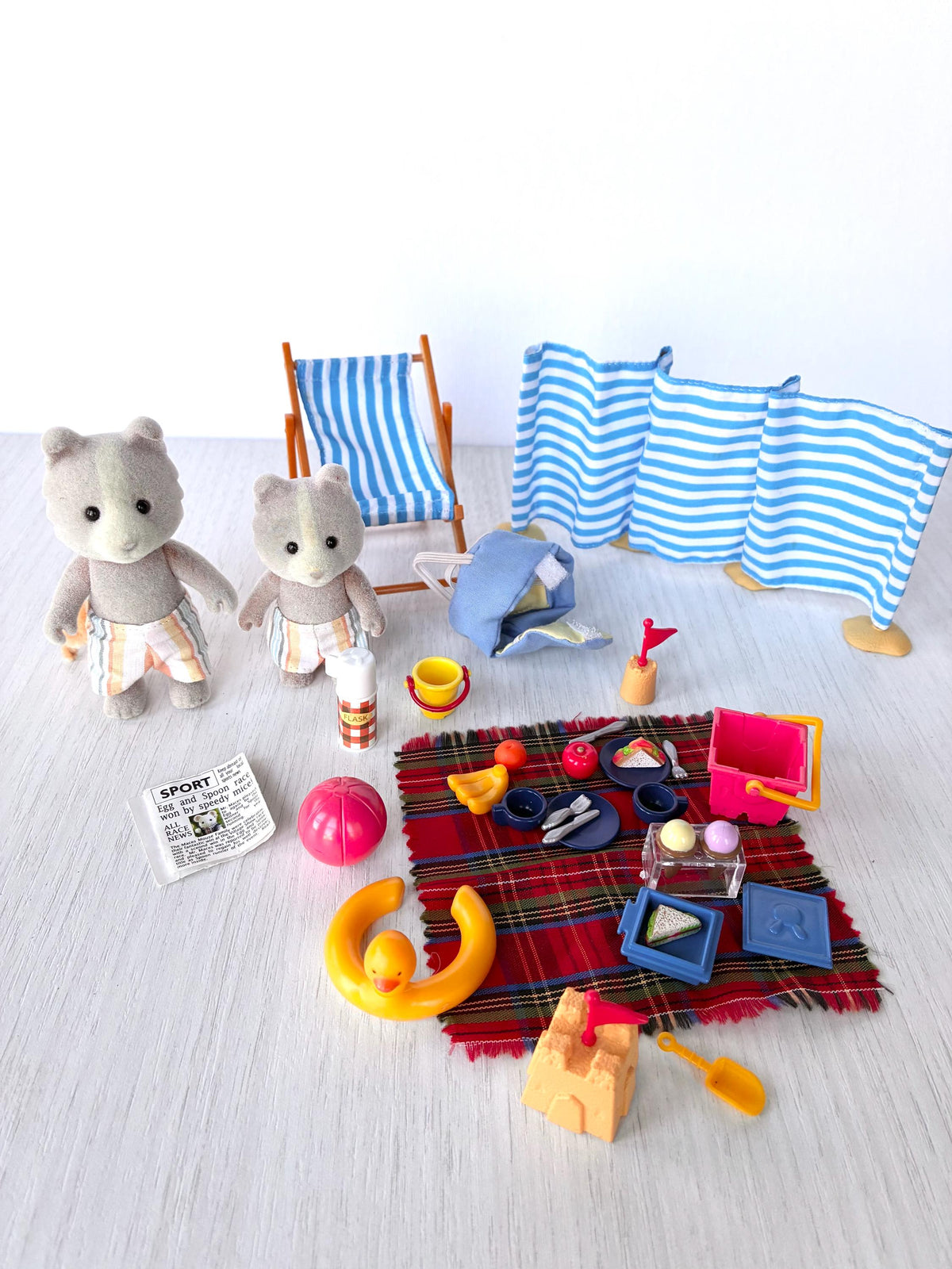 Sylvanian Families Calico Critters Day at the Seaside Set (Flair 4870): everything included laid out, two Farthing dog figures, deck chair, windbreak, rucksack, flask, rug, food, sandcastle and beach toys