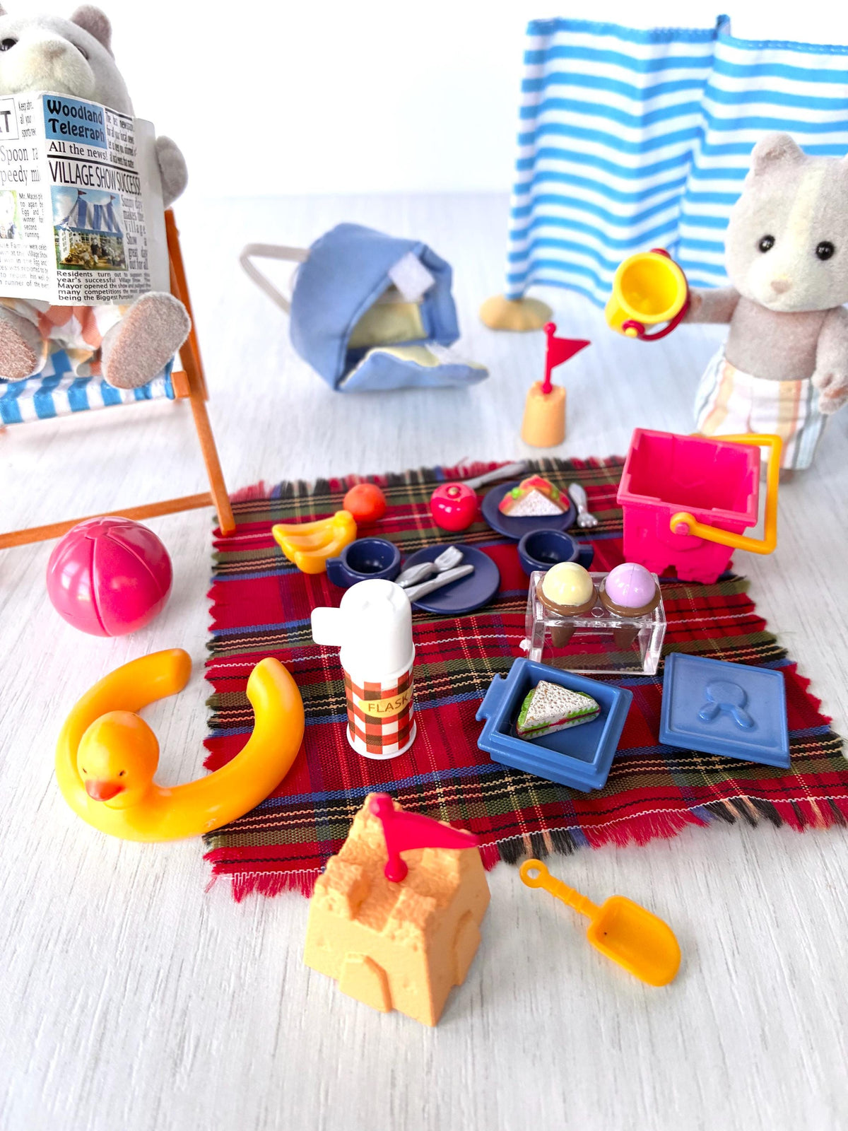 Sylvanian Families Calico Critters Day at the Seaside Set (Flair 4870): close-up of the tartan picnic rug with duck rubber ring, flask, ice cream box, sandwich boxes, sandcastle and spade