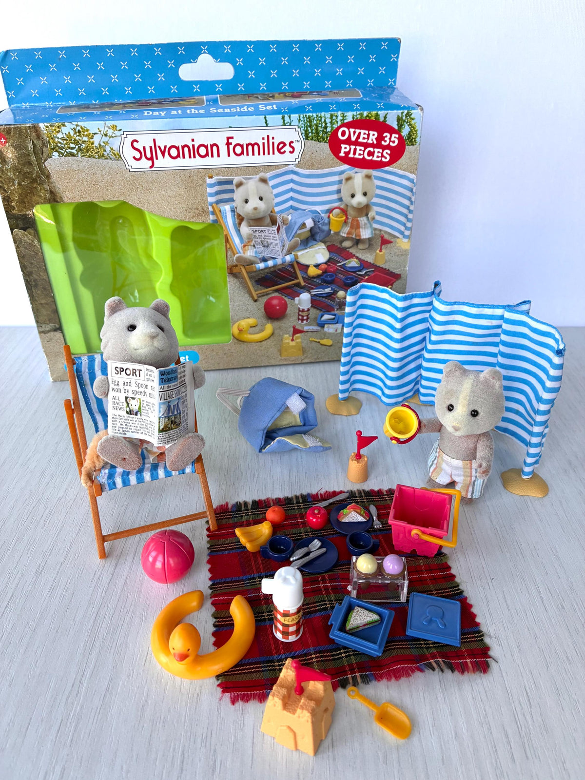 Sylvanian Families Calico Critters Day at the Seaside Set (Flair 4870): full beach scene set up in front of the original Flair box, deck chair, windbreak, rucksack, rug and beach toys