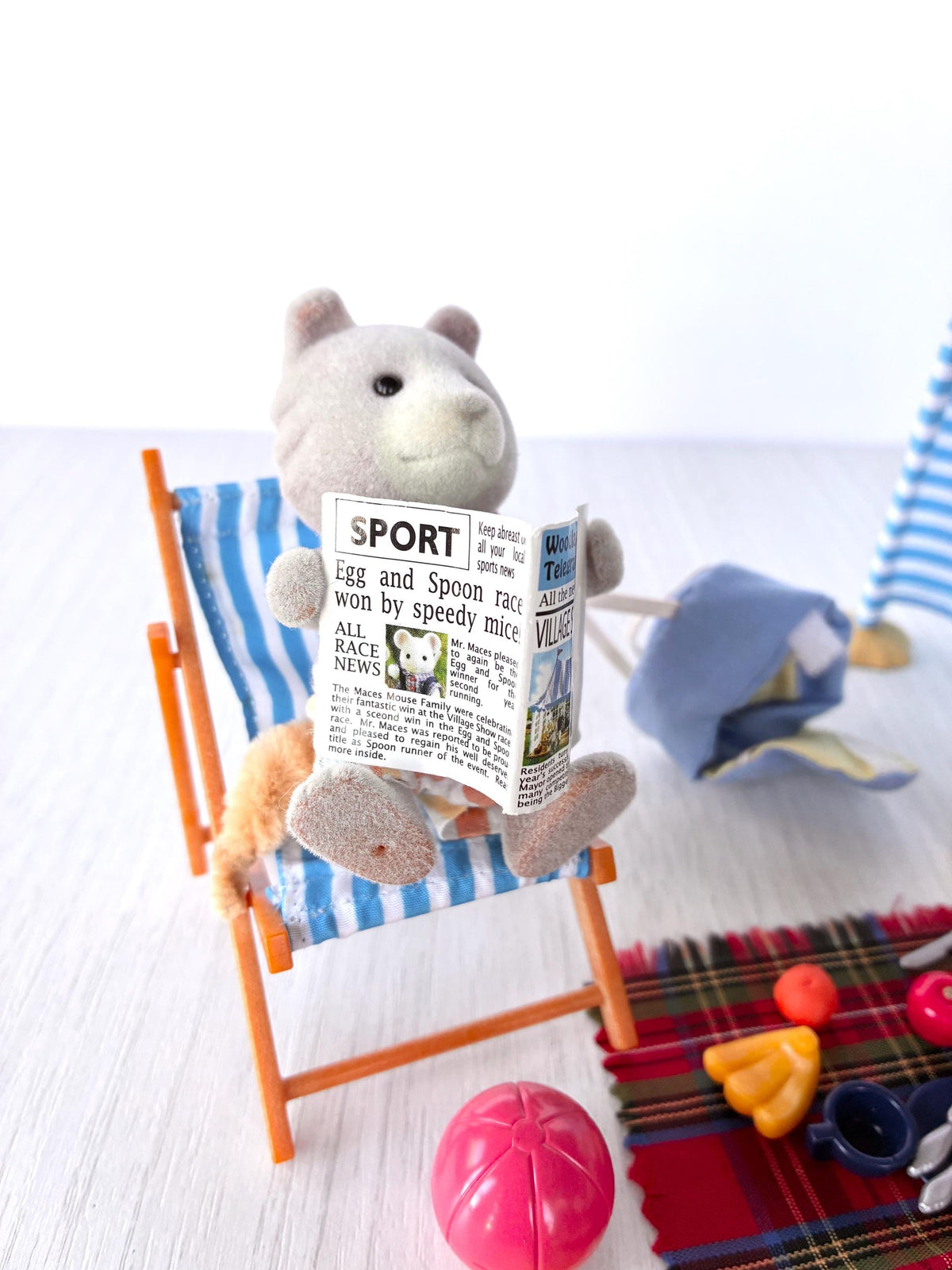 Sylvanian Families Calico Critters Day at the Seaside Set (Flair 4870): close-up of Harley Farthing in the striped deck chair reading the Woodland Telegraph newspaper