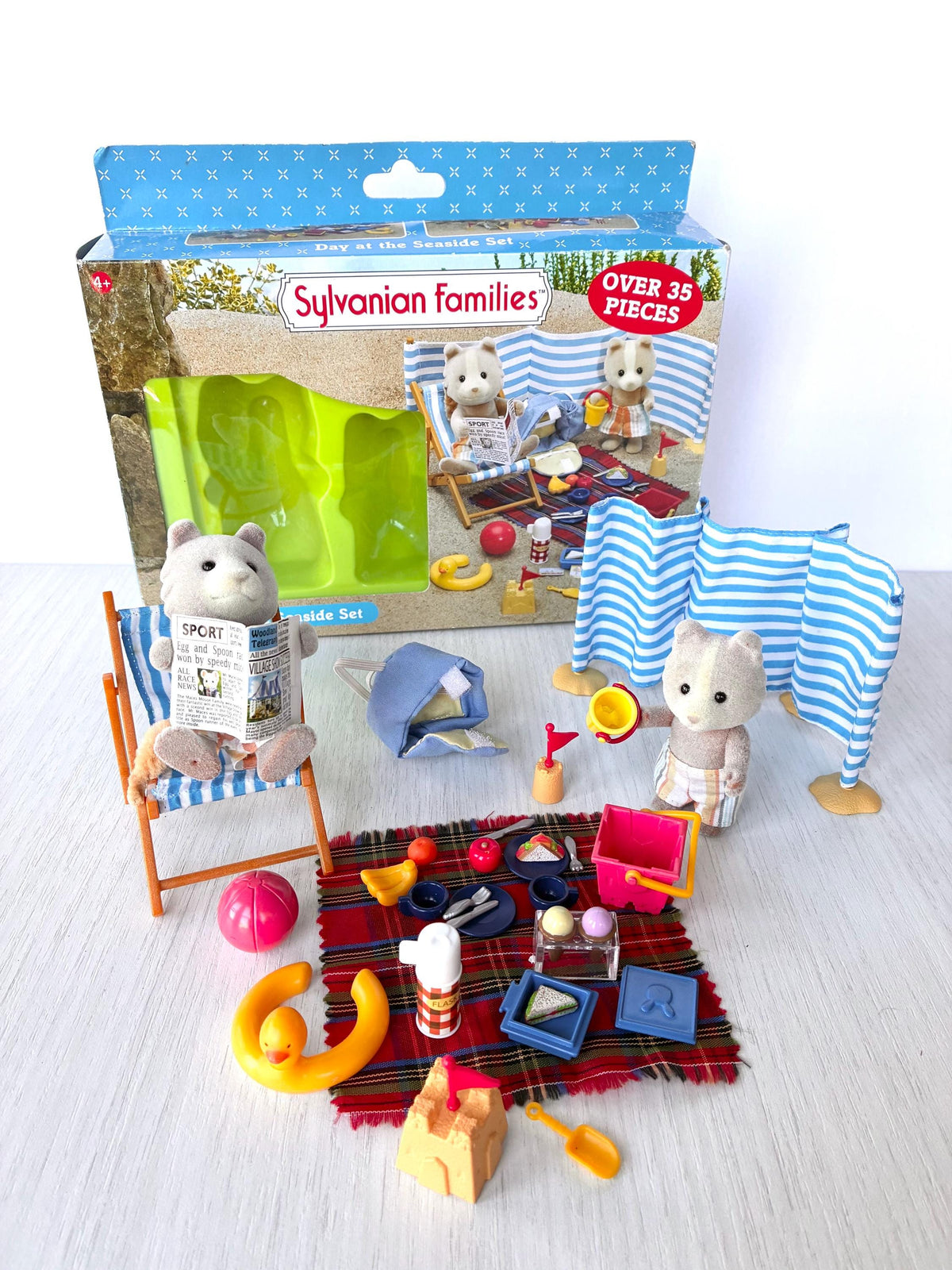 Sylvanian Families Calico Critters Day at the Seaside Set (Flair 4870): wide view of the beach scene and original Flair box, Harley in his deck chair and Vespa by the windbreak