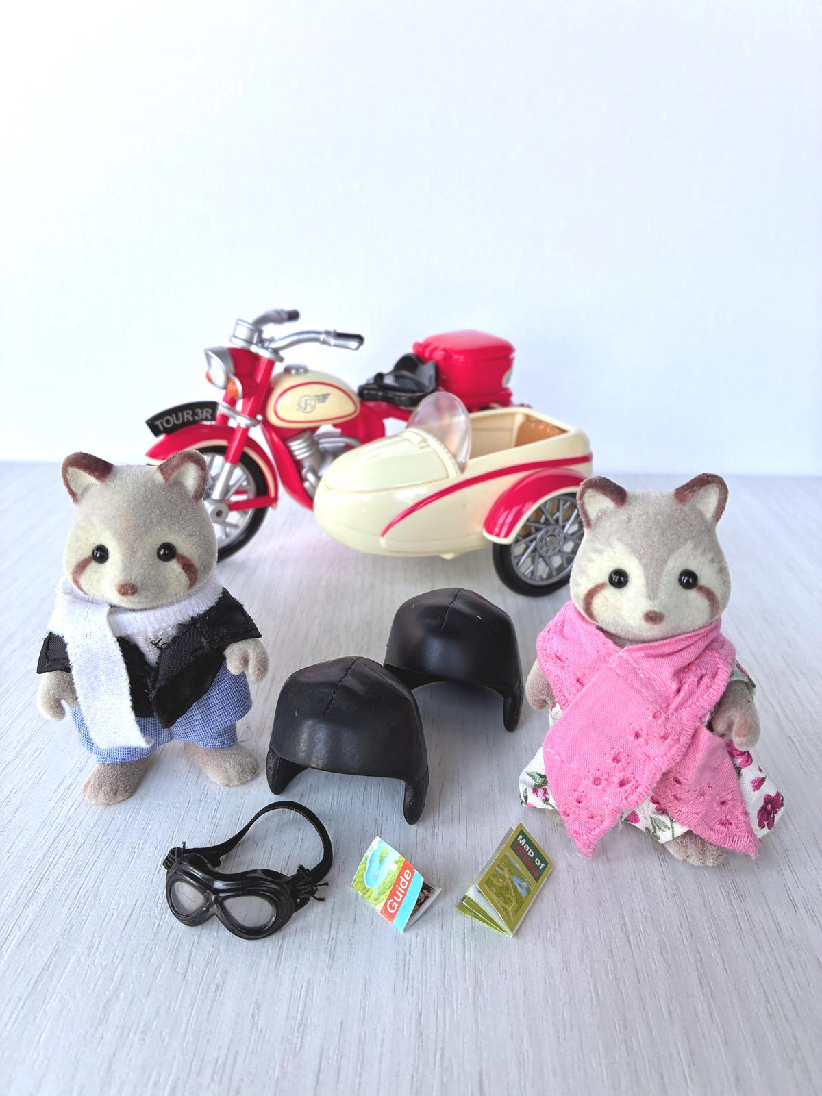 Calico Critters Sylvanian Families Motorcycle and Sidecar Flair 4511 with Mulberry Raccoon Grandparents George and Mildred, two helmets, goggles, guide and map in front of the red and cream bike