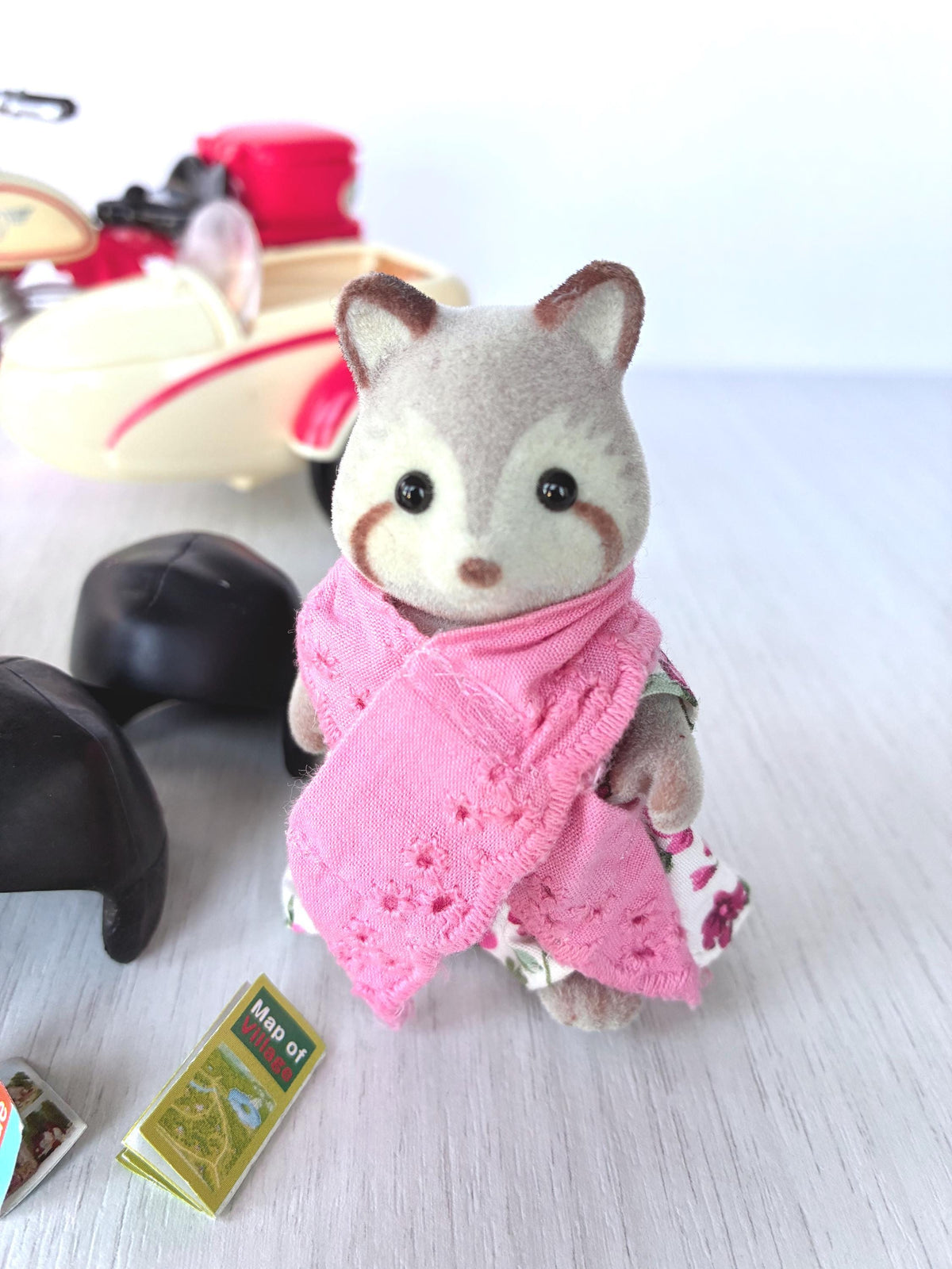 Calico Critters Sylvanian Families Mildred Mulberry Raccoon Grandmother in pink eyelet shawl over floral dress, sidecar and helmet behind her, close-up