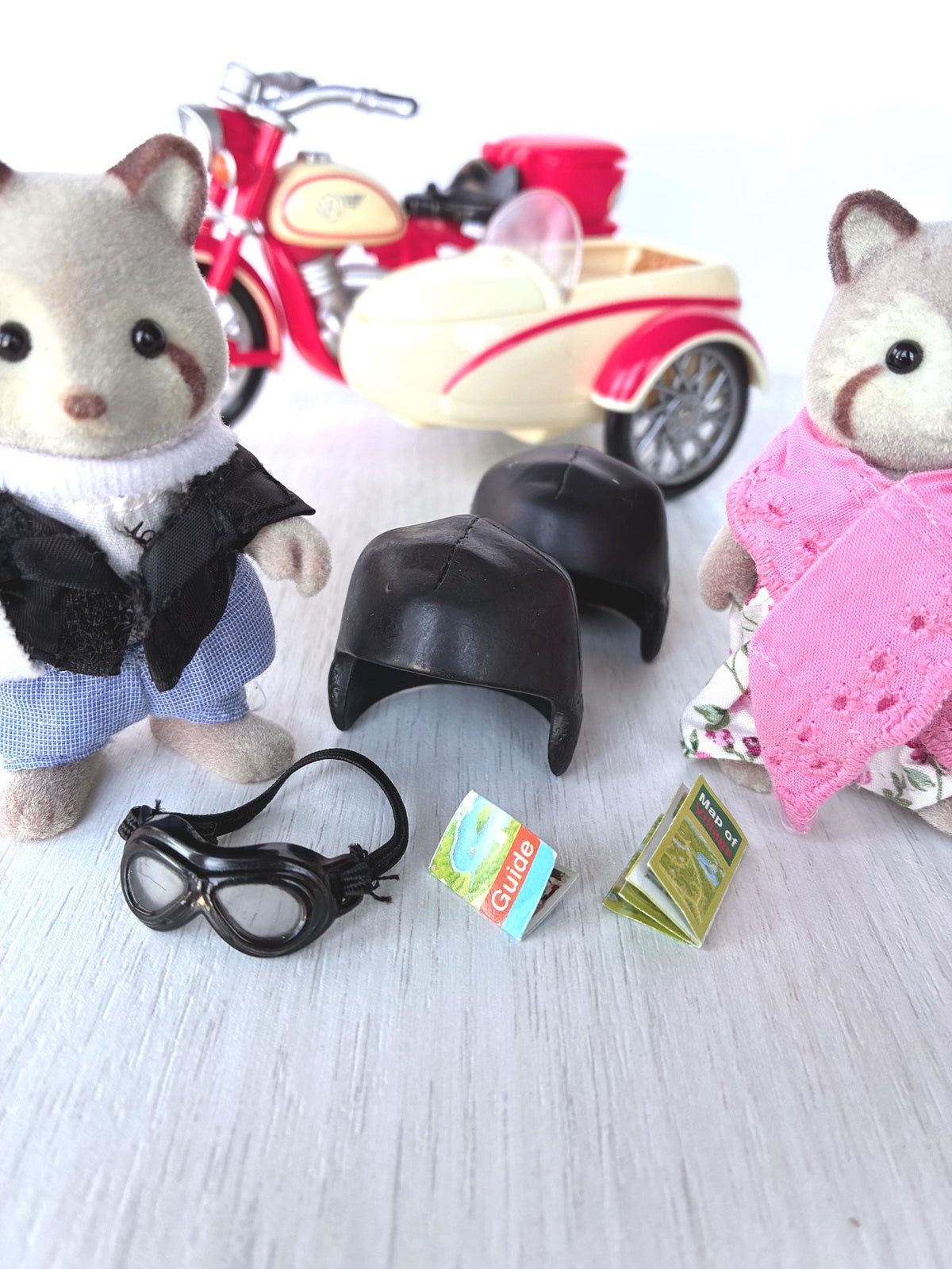Calico Critters Sylvanian Families Motorcycle and Sidecar set accessories: two black riding helmets, goggles, guide booklet and Map of Village with the raccoon grandparents